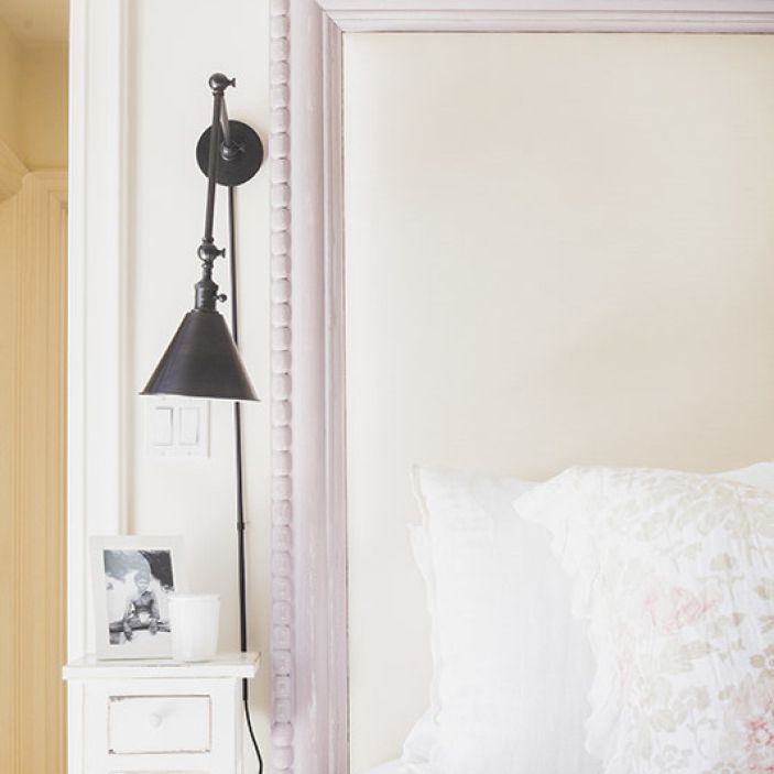 一间卧室，白色的床头板被漆成淡紫色