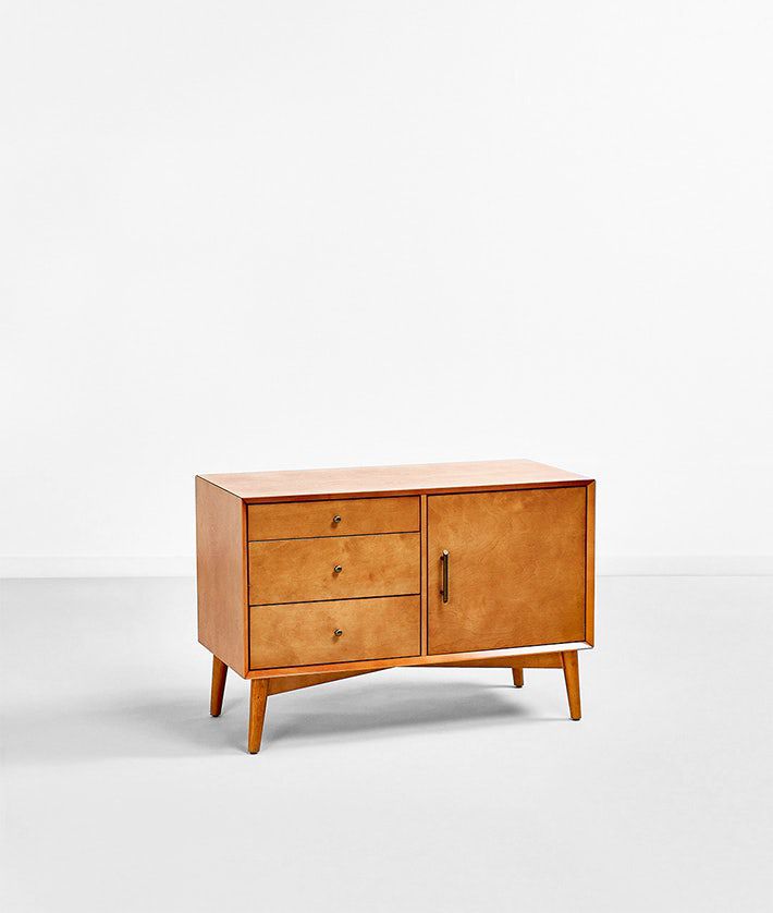 一个蜂蜜色的控制台，有四条腿，三个抽屉和一个橱柜。