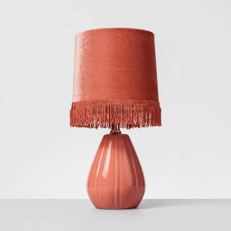 粉红色的陶瓷台灯，带流苏的天鹅绒窗帘。