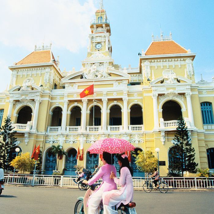 在越南胡志明市的街道上，两名女子骑着摩托车。