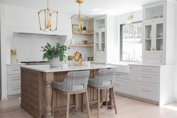 明亮的白色厨房配有木制的岛和金色的五金。