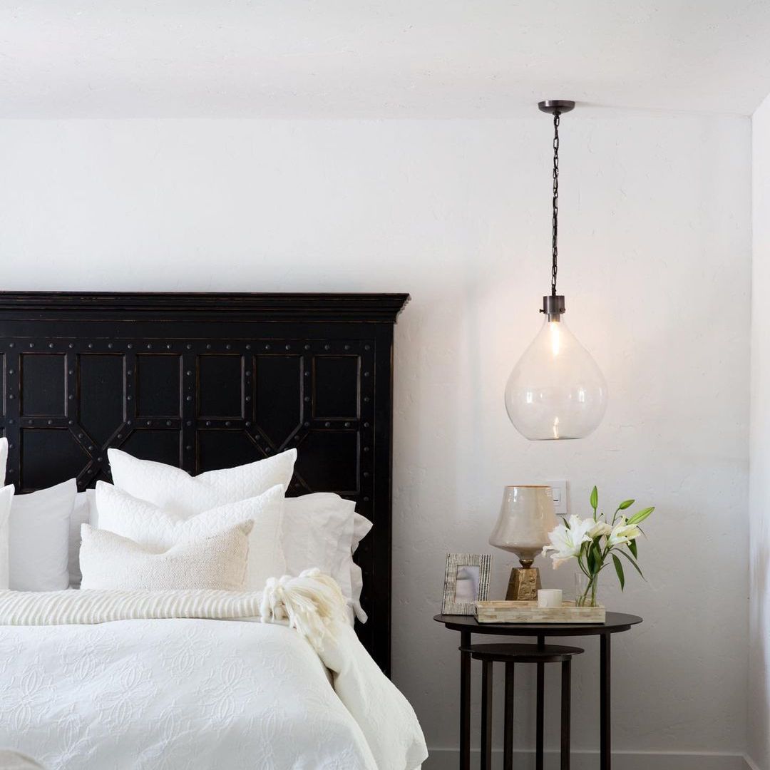 卧室配有大型黑色床框和玻璃吊灯。