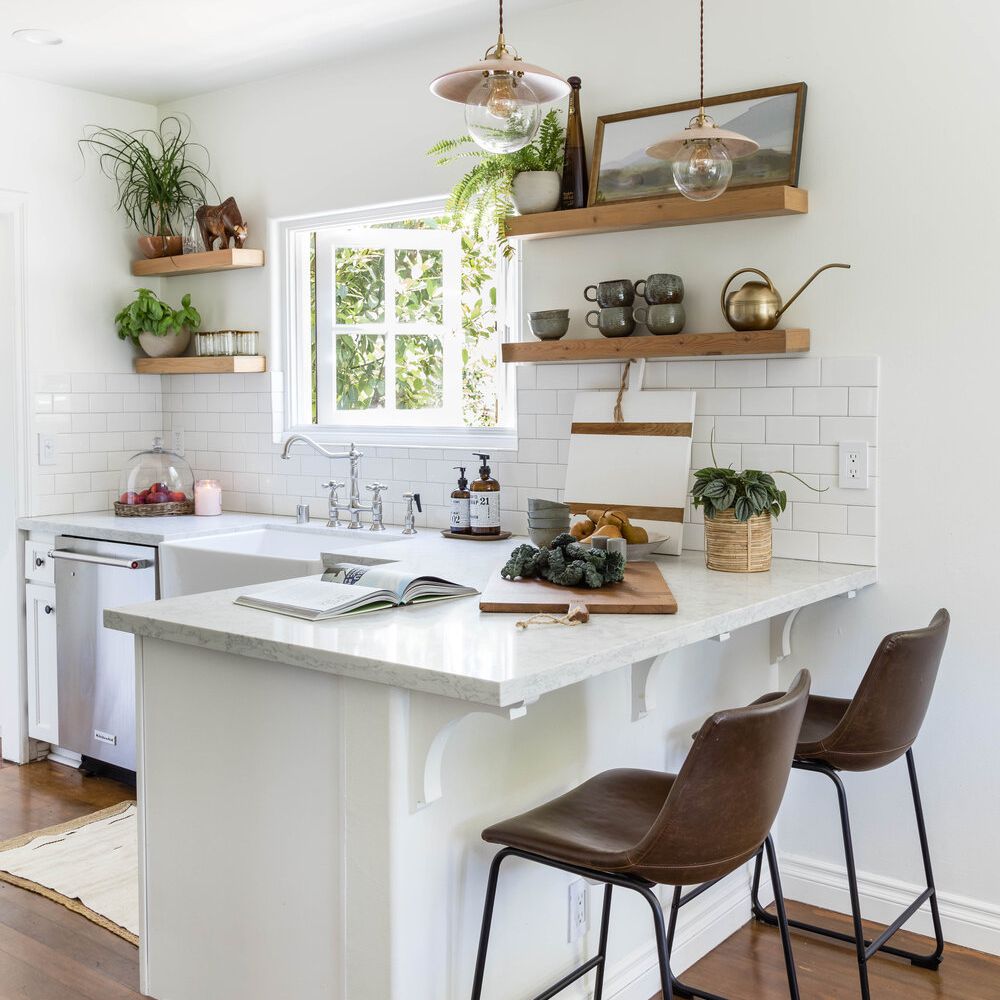 一个白色的小厨房，用几棵植物和颜色协调的厨房用具装饰