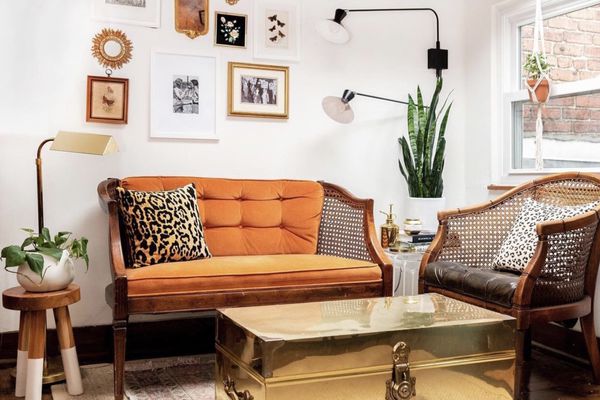 折衷客厅配有橙色沙发，金胸咖啡桌和凳子。