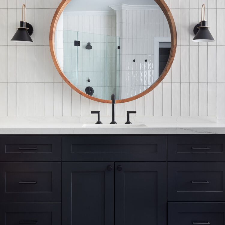 浴室里有海军蓝的橱柜和白色瓷砖的后挡板