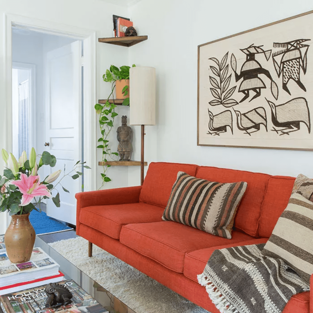 客厅有焦橙色沙发上，装裱艺术和植物的咖啡桌和书架的角落