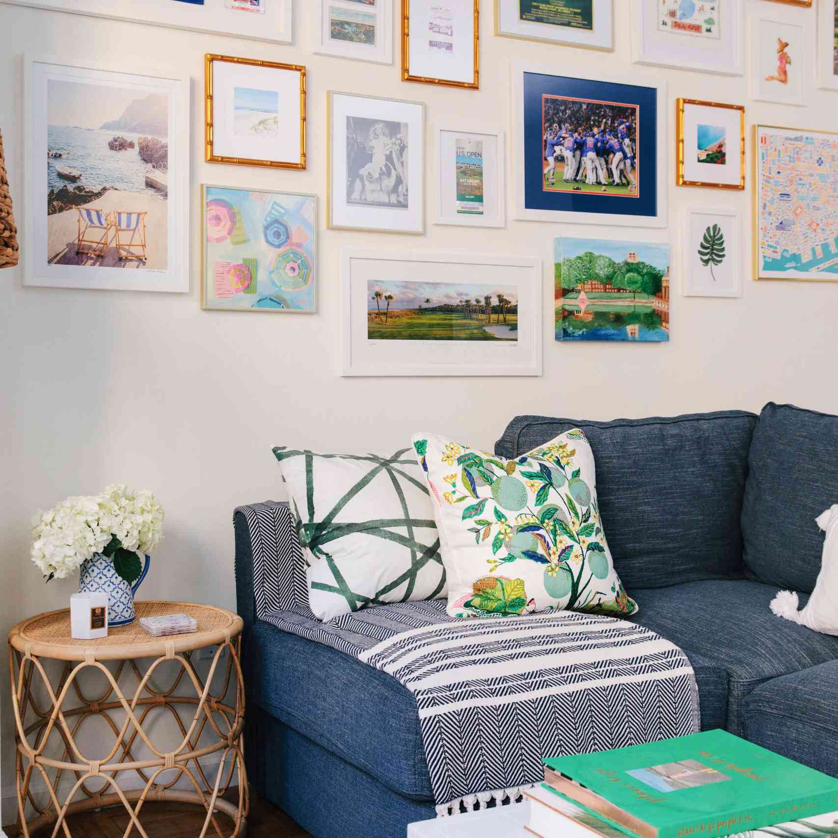 蓝色沙发旁边的藤条口音和画廊墙。