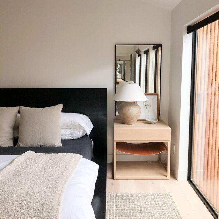 中性卧室有黑色床头板和轻的木侧桌。