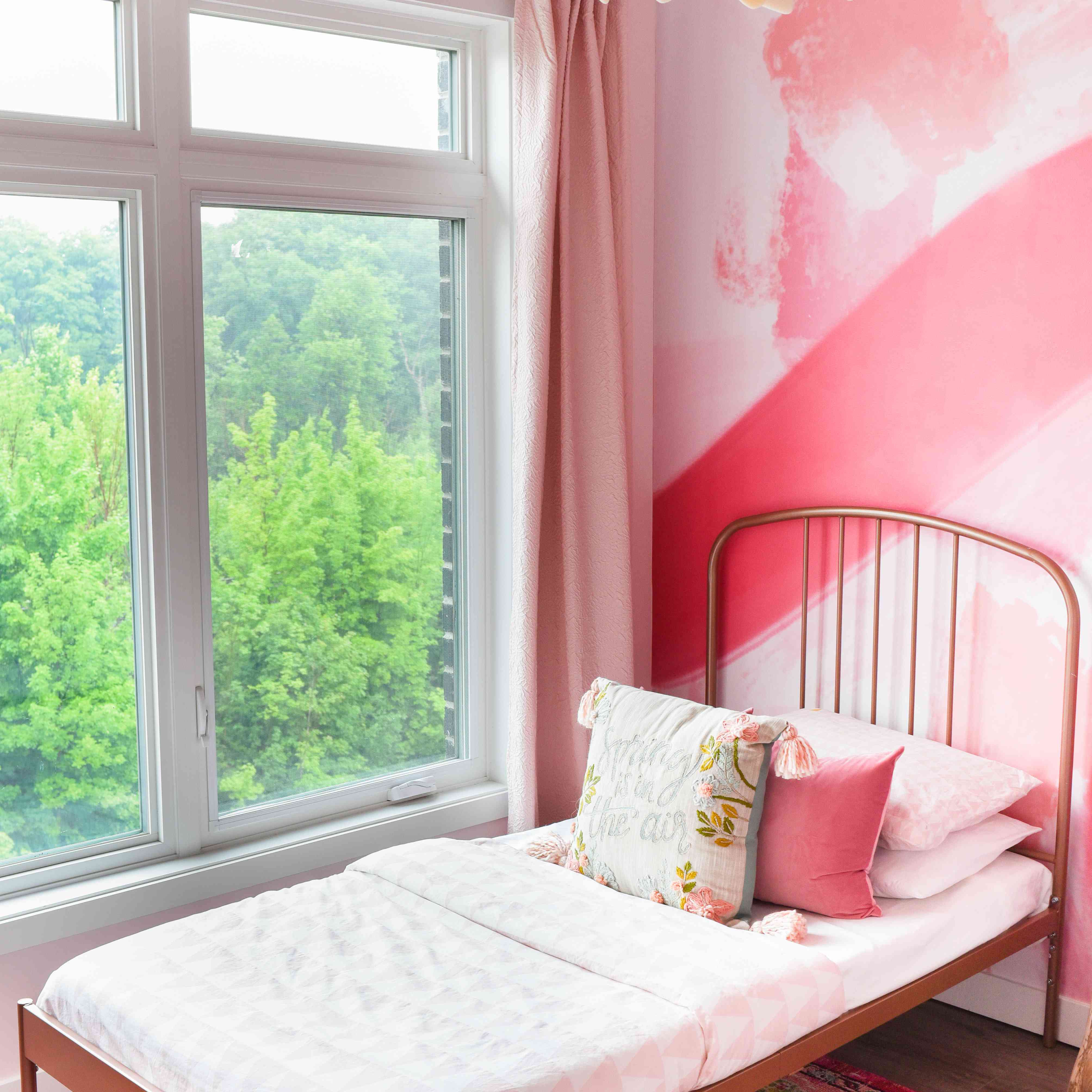 后照片的粉红色卧室与金属双人床框架。＂class=