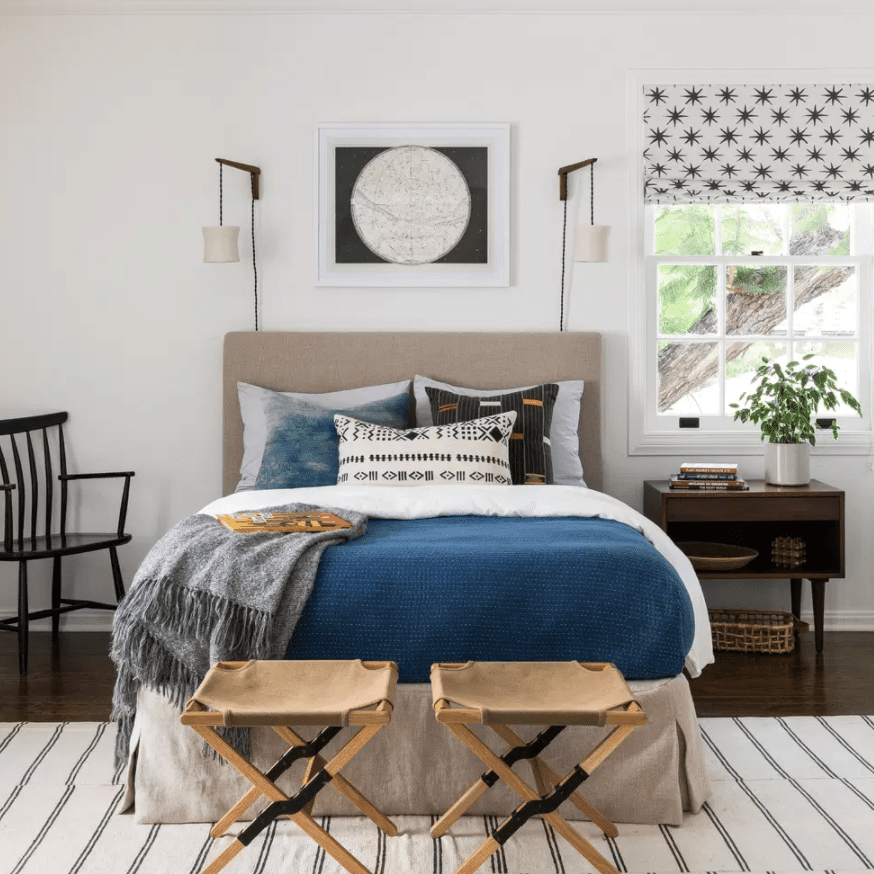 一间有很多存储解决方案的卧室，包括一个床头柜、一个篮子和两个行李架(已经放在床脚)