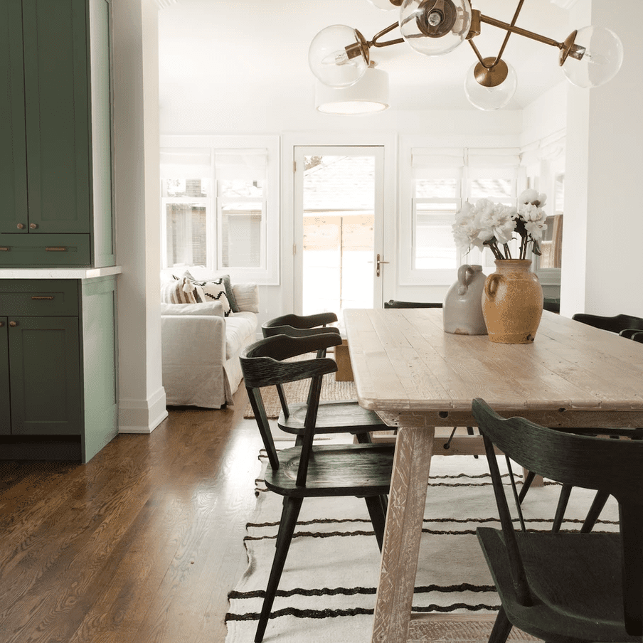 一个木制的餐桌，上面有一个米色的陶瓷花瓶和一个装满鲜花的橙色陶瓷花瓶