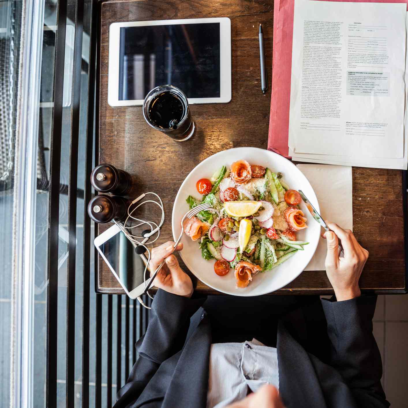 的某人单独外出就餐在工作和读书的俯视图。