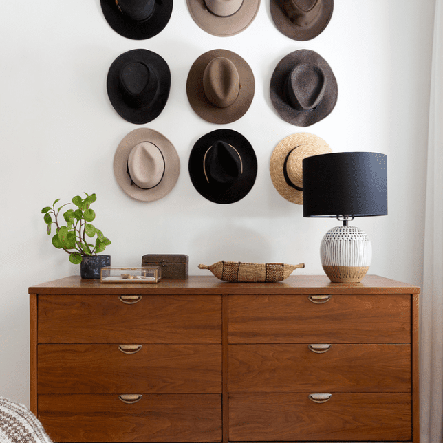 卧室的墙上装饰着一张控制台桌和九顶帽子