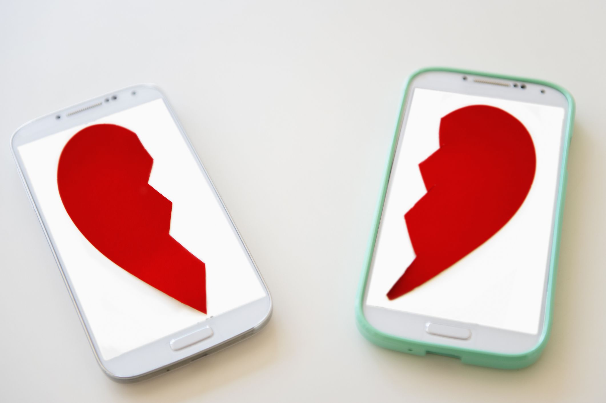 两款智能手机，每个屏幕上的红色破心脏的一半。