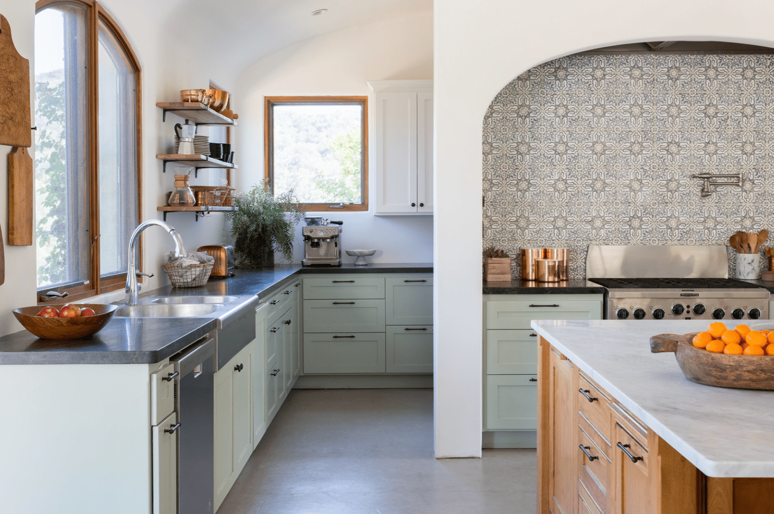 一个厨房，有薄荷橱柜、一块印花瓷砖后挡板和一个煤气炉