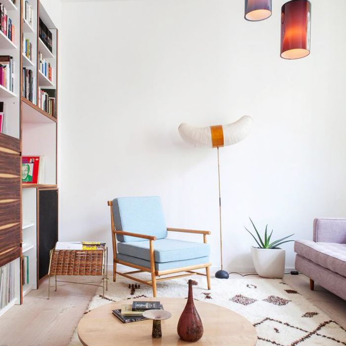 客厅里的扶手椅旁边有一面墙的书和一个杂志架