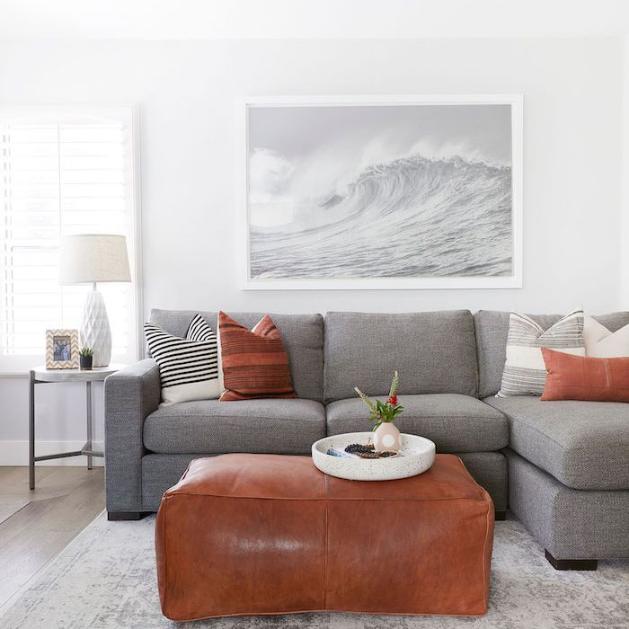 灰色和棕色的现代客厅，皮革奥斯曼用作咖啡桌