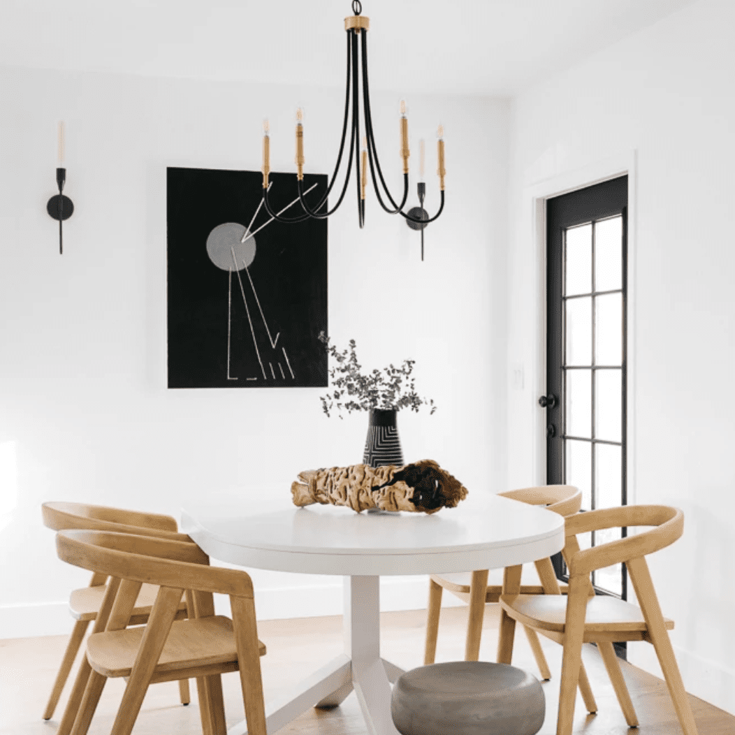 一张白色的餐桌，摆着一个装满鲜花的花瓶和一根挖空的大浮木