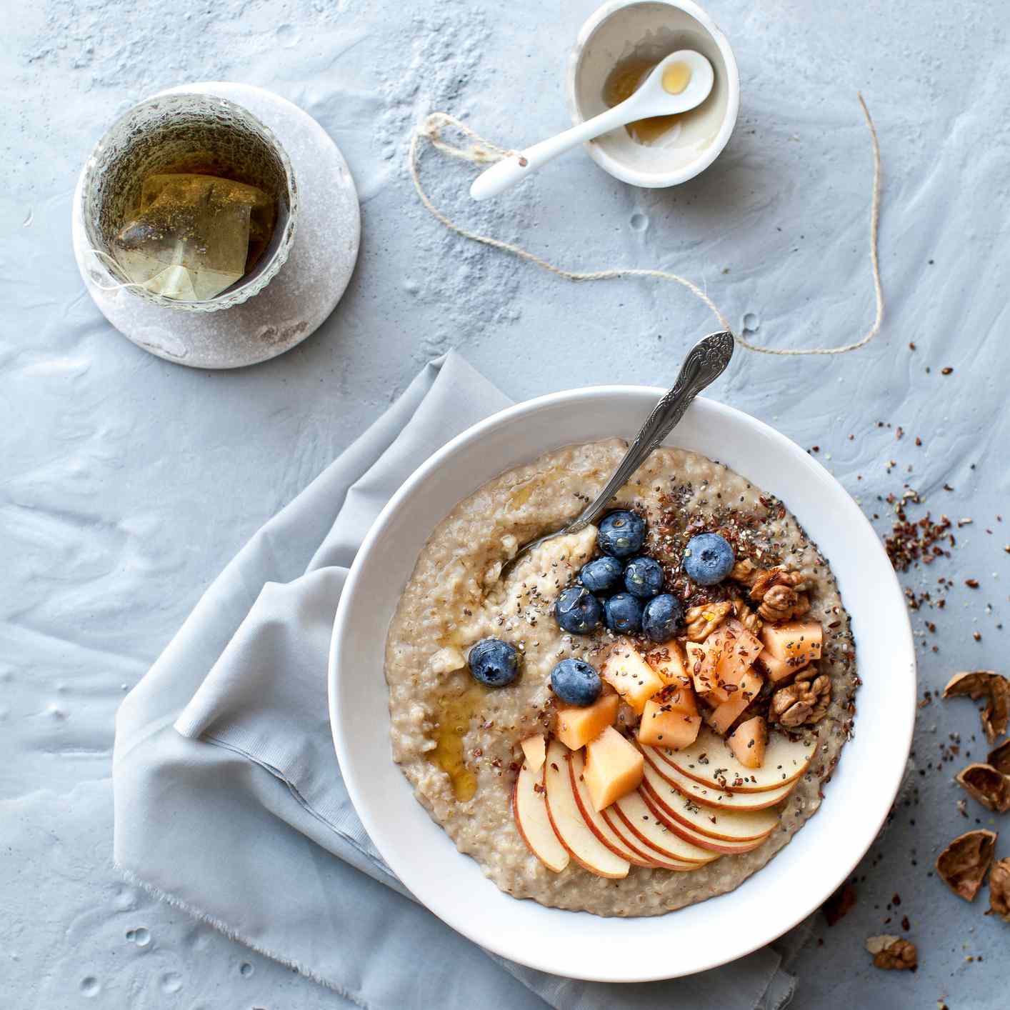 燕麦的碗淋上蓝莓和苹果片和热茶端