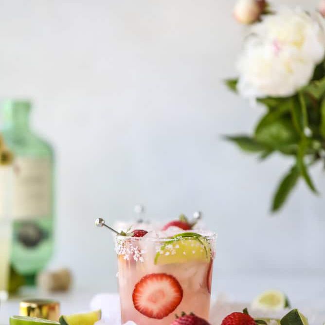 加草莓和酸橙的玛格丽塔酒。背景是花。