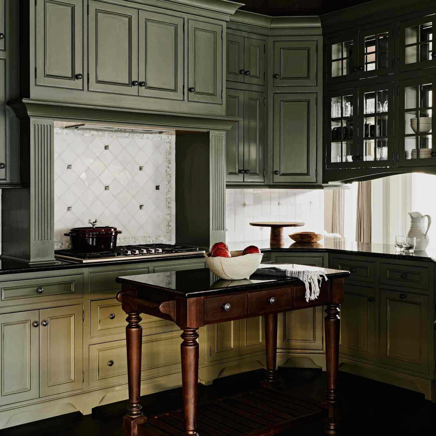 厨房里有薄荷绿色的橱柜和白色瓷砖的后挡板，后挡板由较小的灰色瓷砖构成