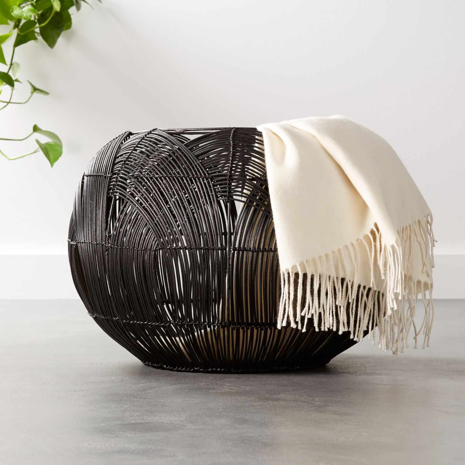 用毯子的圆形黑色编织藤篮搭着侧。