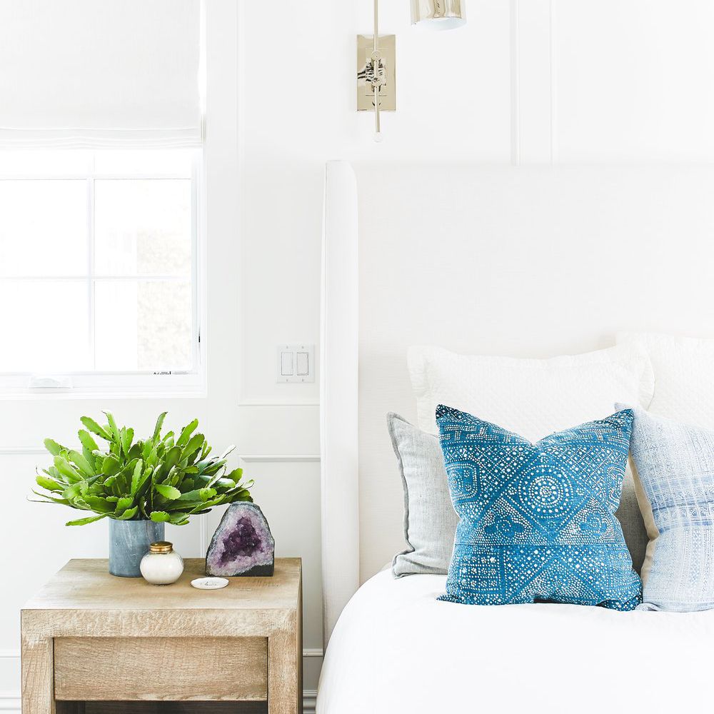 一间带蓝色枕头的全白色卧室和大胆的紫水晶吉祥音