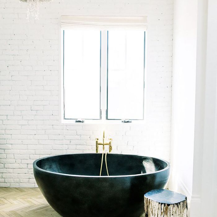 白色砖砌浴室，圆形浴缸和吊灯。