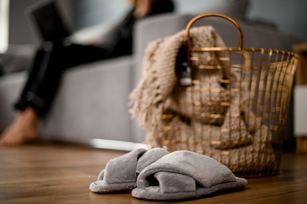 大金属柳条篮子，里面有针织毯子，附近有拖鞋