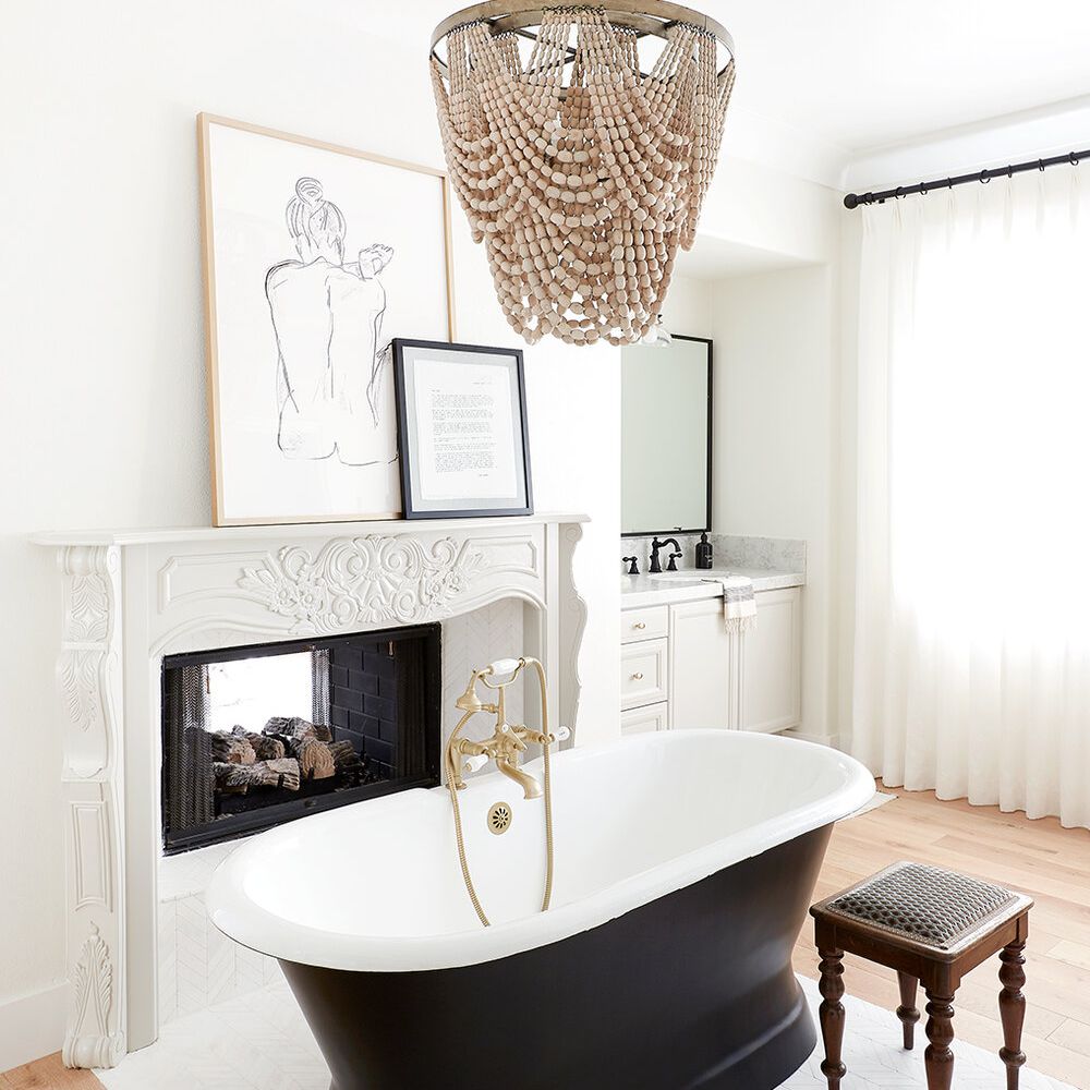 带黑色浴缸和串珠枝形吊灯的时尚的白色浴室