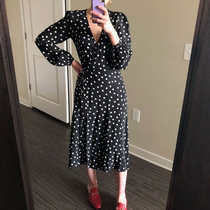 一位女士穿着黑白圆点花纹连衣裙和红鞋。