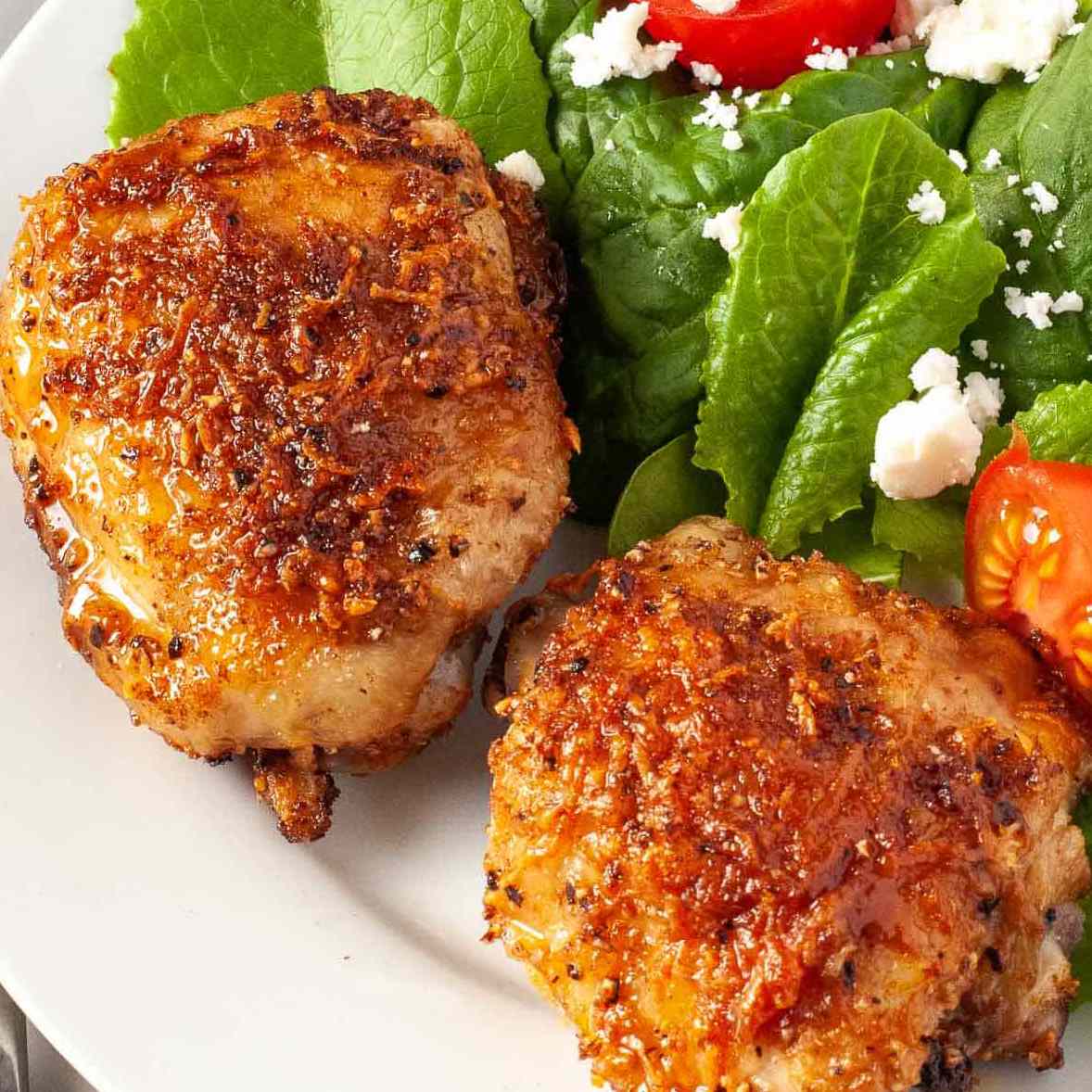 两份帕尔马干酪鸡胸肉放在沙拉旁边的盘子里