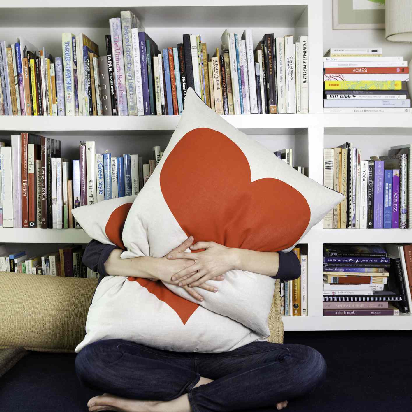 有人爱自己，抱着两个枕头，枕头上有心形图案。