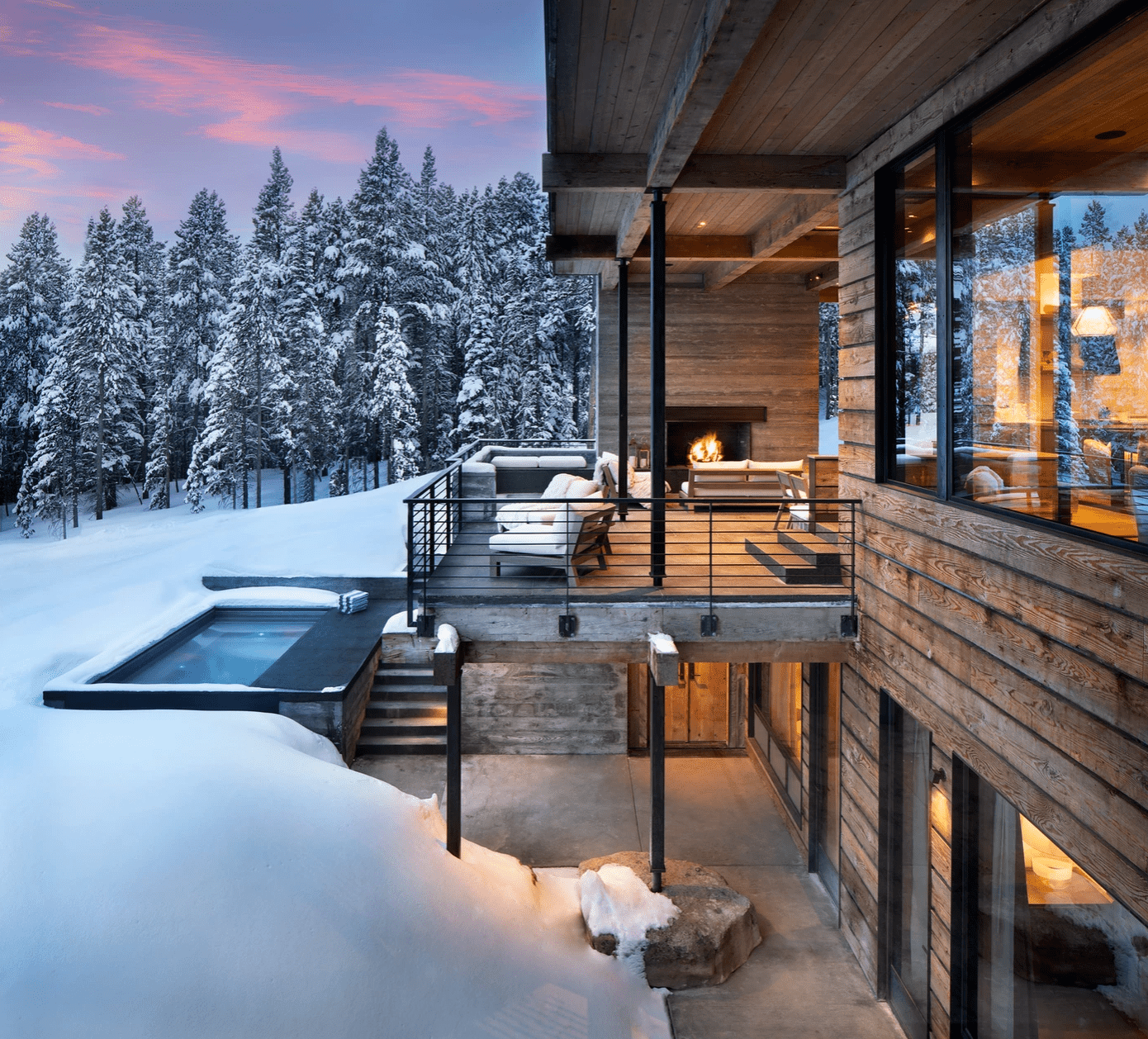 一个带户外壁炉的大型覆盖的门廊，位于雪山中间