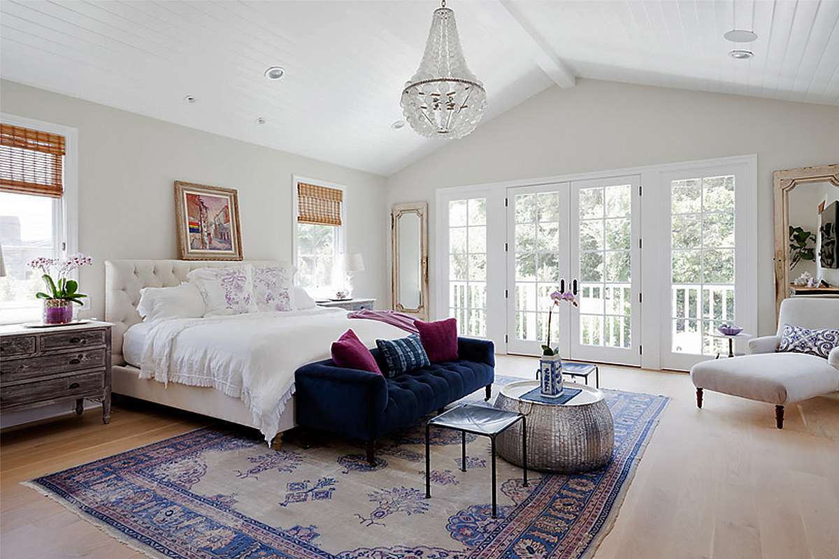 通风的全白色的卧室，配有吊灯和海军簇绒天鹅绒沙发。