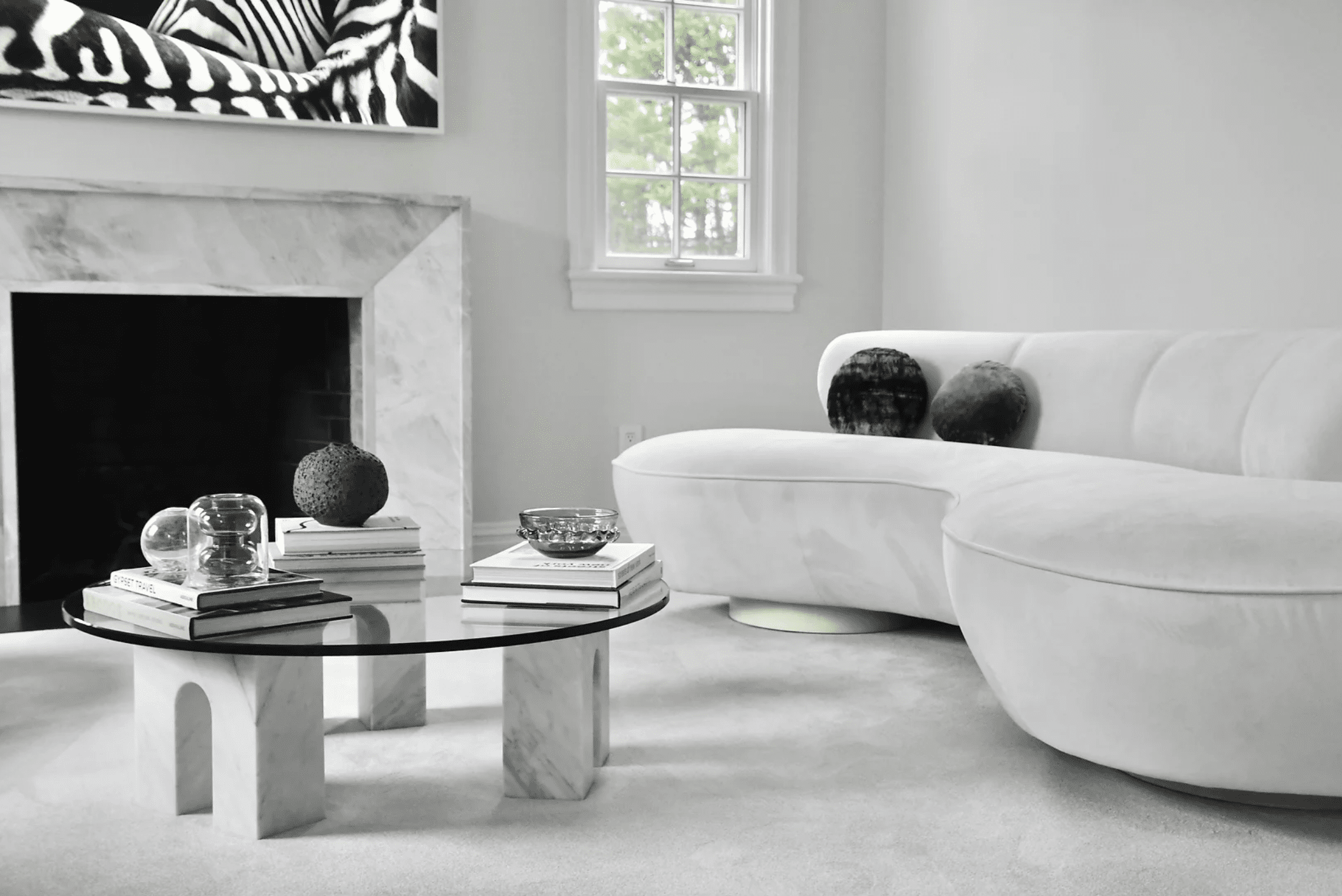 一间白色和浅灰色的客厅，有一座大理石壁炉和配套的咖啡桌