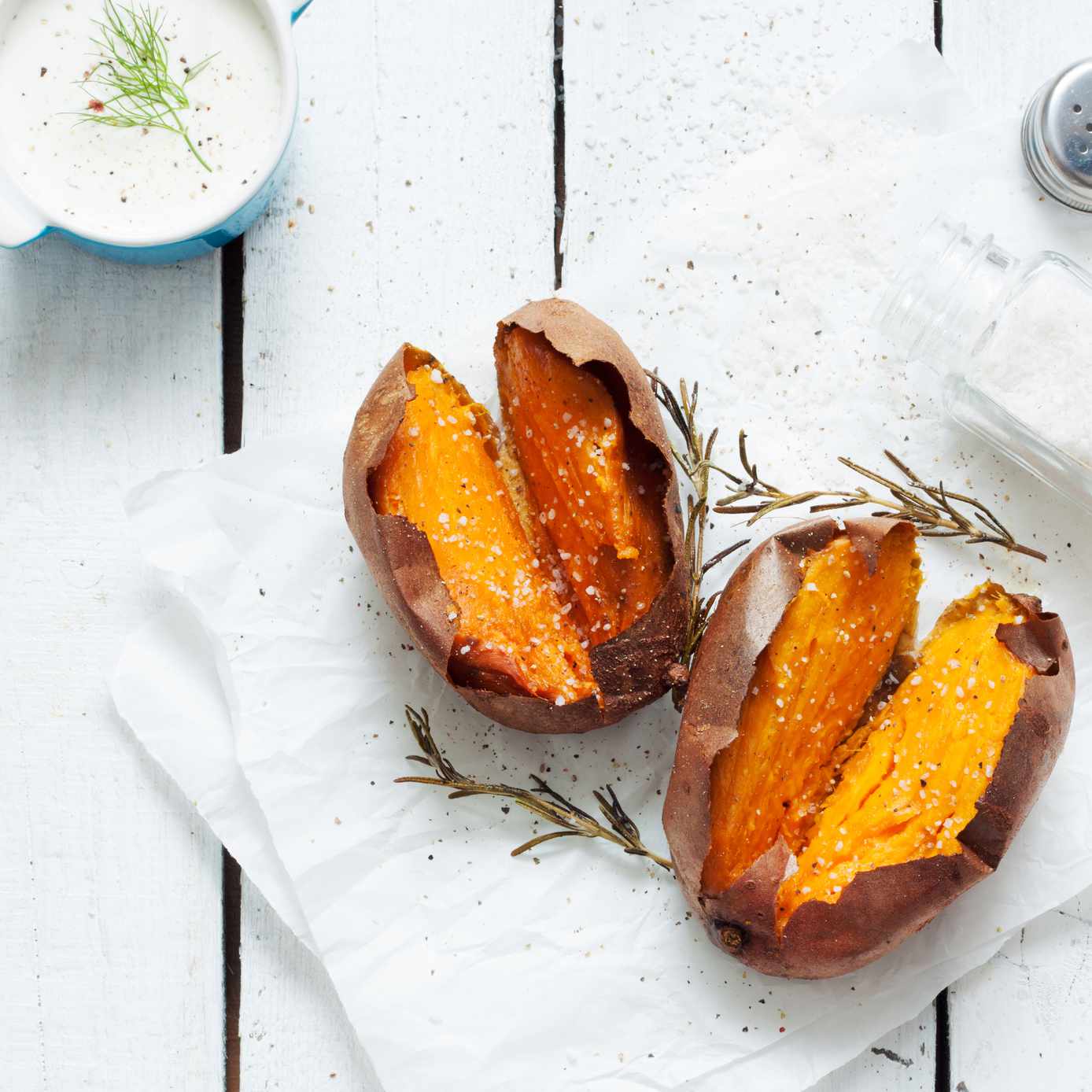 烤红薯，蘸酱，盐和迷迭香。白色的木制乡村野餐桌上的风景。