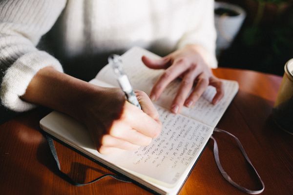 一个女人坐在窗户光线和期刊的桌子。