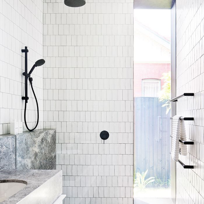 用白色瓷砖墙壁和灰色瓷砖地板的浴室。