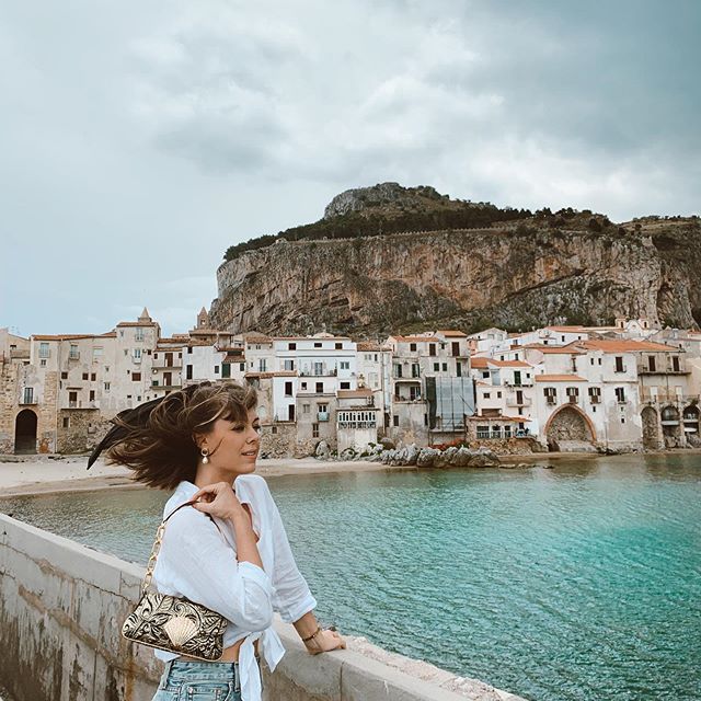 一个女人站在桥上，虽然在国外旅行观光。