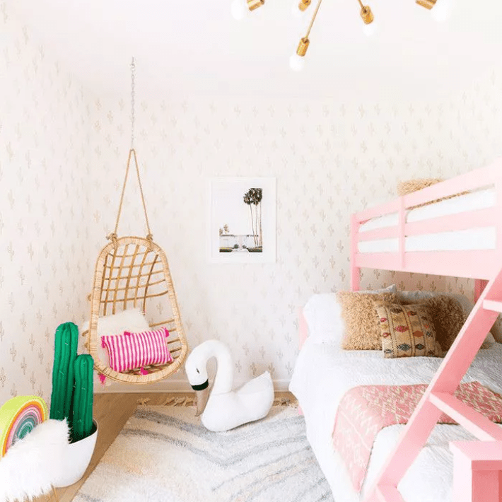 青少年卧室的陈述黄铜吊灯挂藤椅和粉红色的双层床。