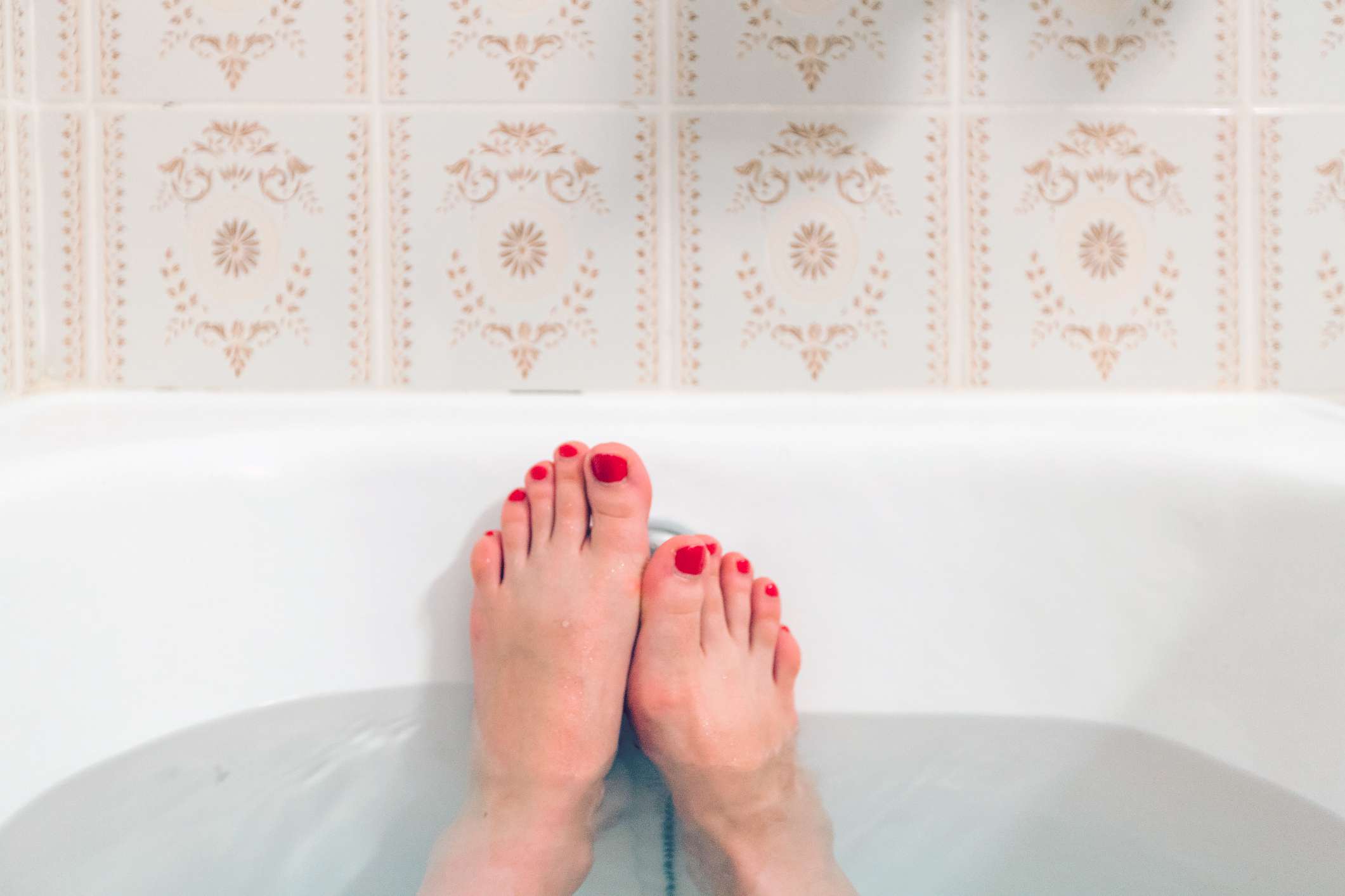 两只脚伸出一个装满水的浴缸。