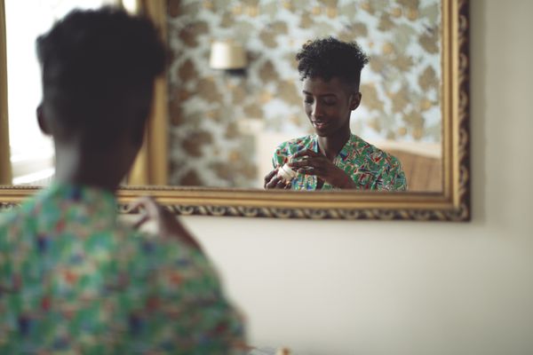 一个女人看着镜子里映出的面霜。