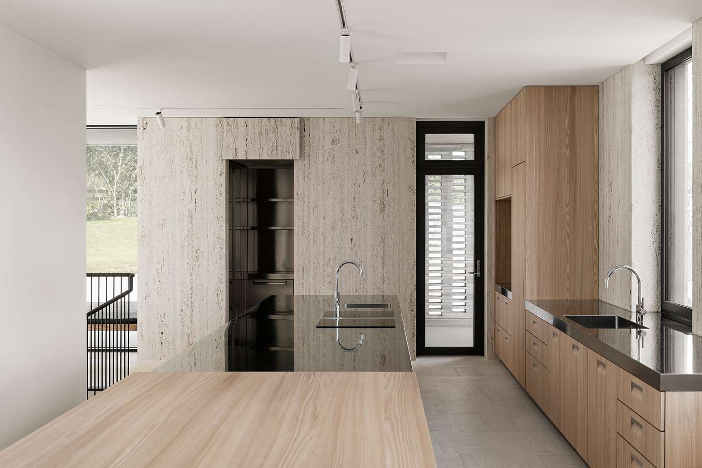 厨房里有浅色的木橱柜，大理石装饰，还有一个玻璃炉灶