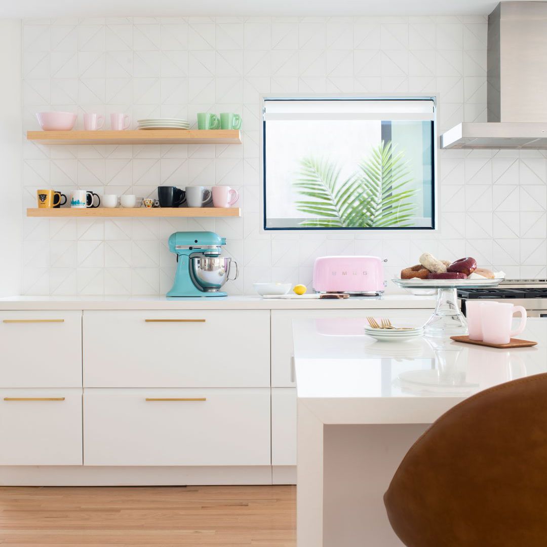 一个白色的小厨房，厨房用具颜色协调，三角形瓷砖内衬后挡板