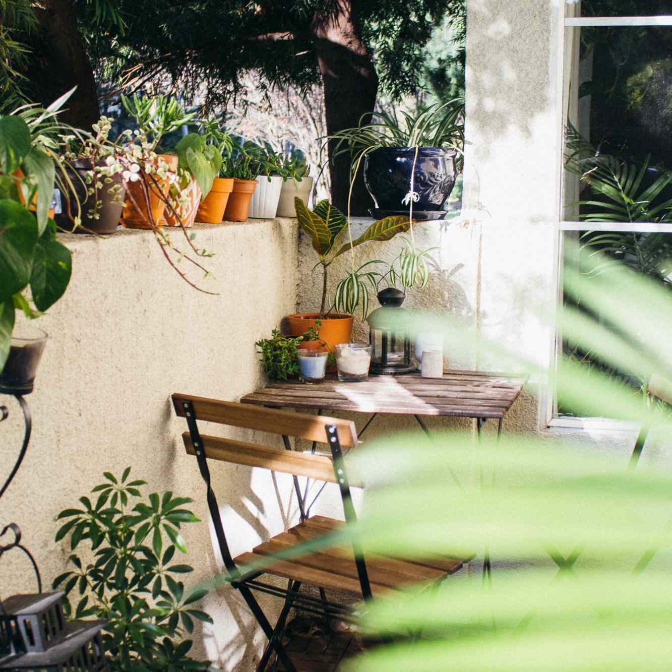 一个小阳台装饰着一张小酒馆的桌子，两把椅子，和大量的植物
