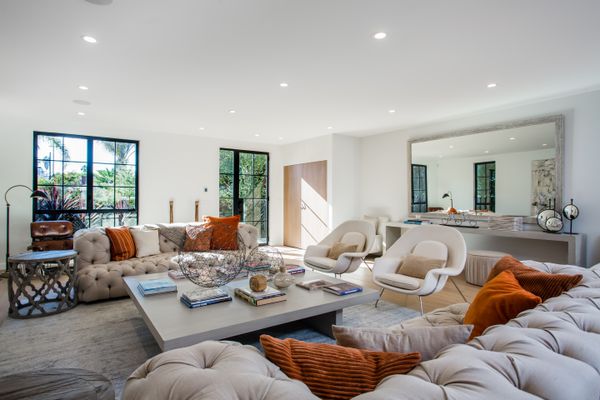 宽敞的客厅里有中性的沙发和焦橙色的枕头