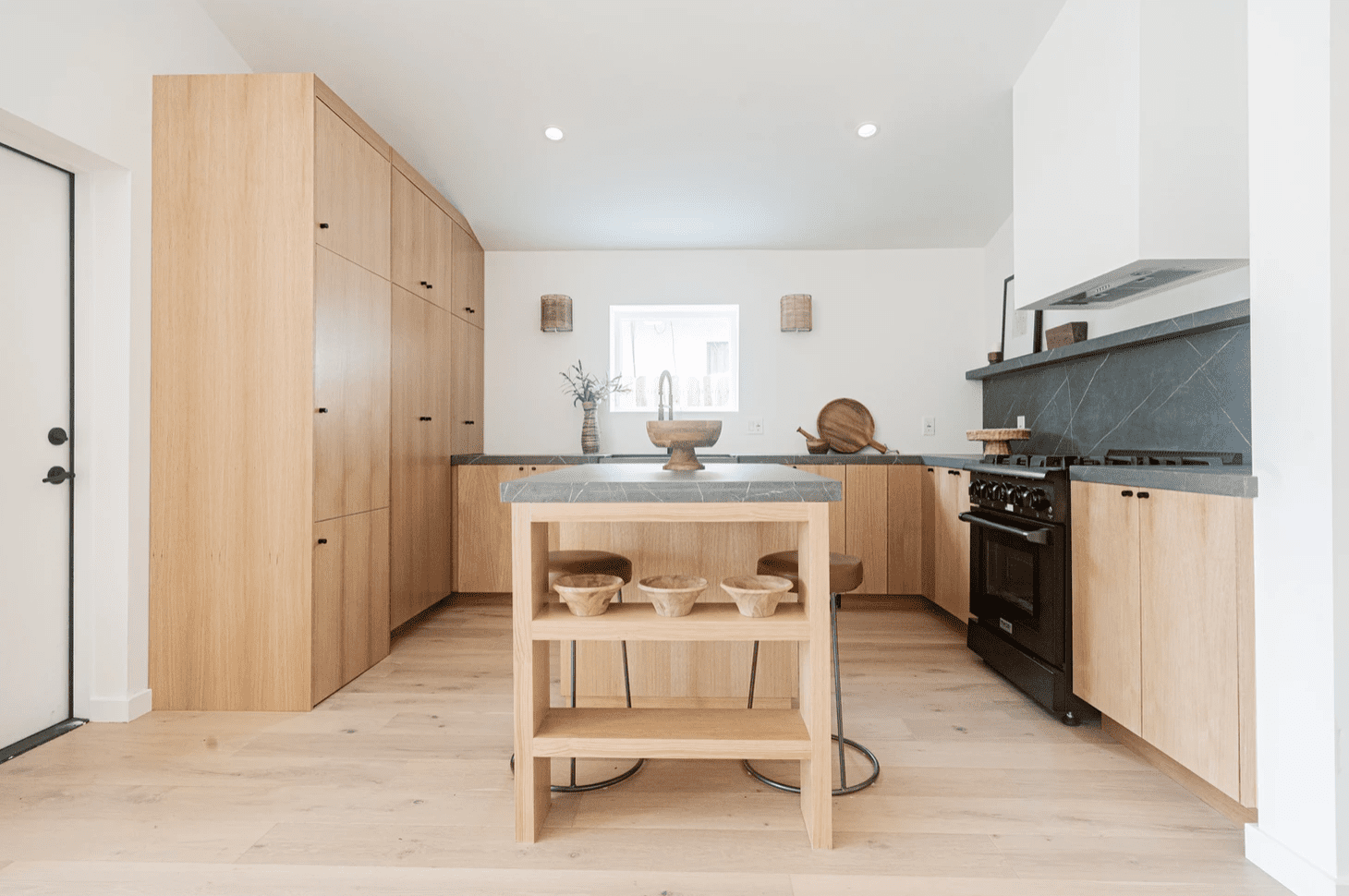 厨房里有轻木橱柜和炭质大理石后挡板