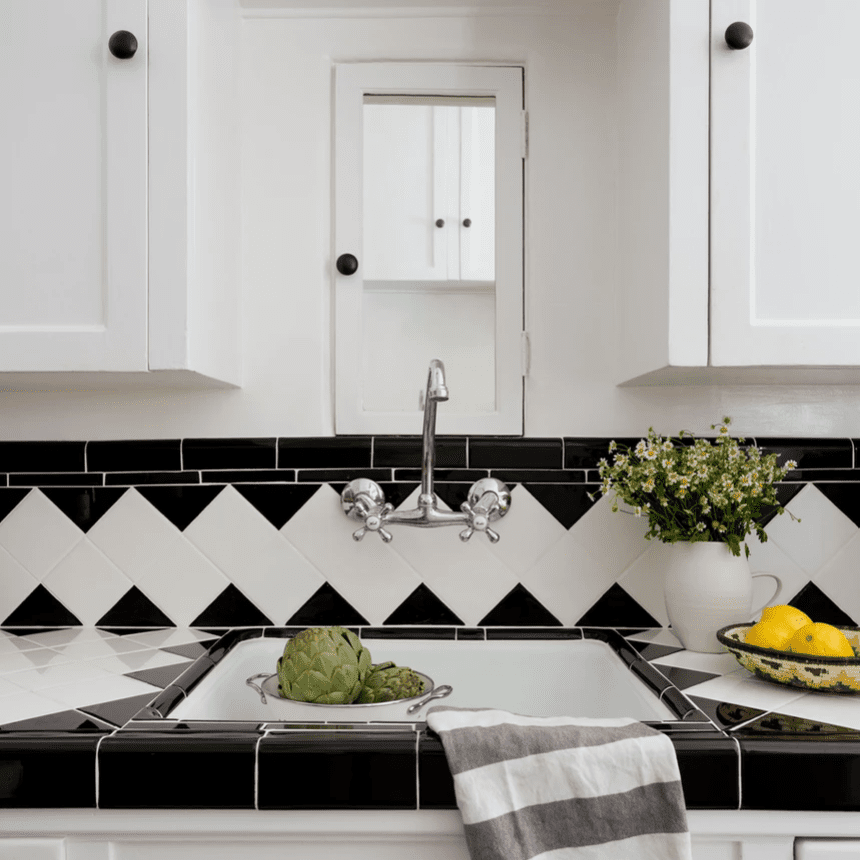 一个全白色的厨房，带黑色和白色的瓷砖壁板