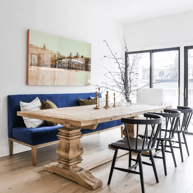 一张厨房用桌子，一边有一个天鹅绒沙发和另一张餐厅椅子上